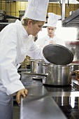 Female chef examining the contents of a pan