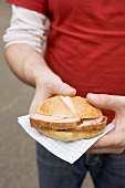 Person holding roll filled with Leberkäse (type of meatloaf)