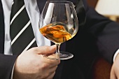 Mann schwenkt Cognac im Glas