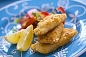 Breaded fish fillets with pepper salad and lemon wedges
