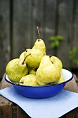 Fresh pears in blue dish on wooden crate