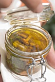 Hand holding jar of pickled mushrooms