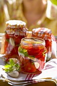 Pickled tomatoes in jars, woman in background