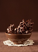 Chocolate-coated almond clusters in brown bowl