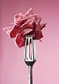 Candied rose held in tongs