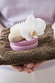 Woman holding towel, soap, brush and orchid