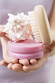 Hands holding soap, shell and brush