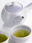 Two bowls of green tea in front of teapot