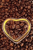 Coffee beans, some in heart-shaped dish (overhead view)