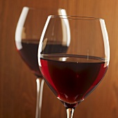Two glasses of red wine against wooden background