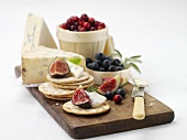 Crackers with fruit and blue cheese on chopping board