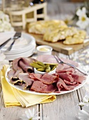 Ham and pastrami platter with gherkins on buffet