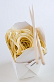 Noodles in take-away box with chopsticks