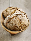 Two loaves of organic bread in wooden bowl