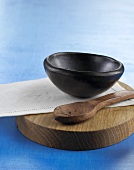 Black bowl, napkin and wooden spoon on wooden board