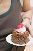 Woman holding small chocolate cake with red hearts