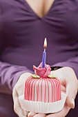 Woman holding small marzipan cake with a candle