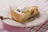 Piece of apple tart with flaked almonds and cream