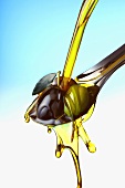 Pouring olive oil over olives on spoon