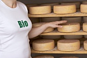 Woman reaching for a cheese on a wooden shelf