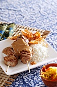 Chicken satay kebabs with peanut sauce, rice and crisps