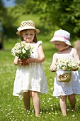 Two girls in a summer meadow holding daisies