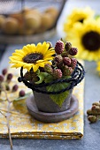 Gesteck aus Sonnenblume und Brombeerzweigen