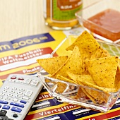 Sports newspaper, tortilla chips and remote control