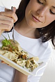 Young woman eating filled pasta