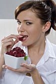 Young woman eating fresh raspberry