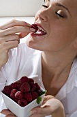Young woman eating fresh raspberry