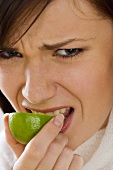 Young woman biting into half a lime