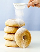 Dusting giant lemon doughnuts with icing sugar