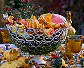 Ornamental gourds and rose hips in metal basket