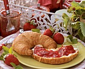 Croissant with butter and strawberry jam
