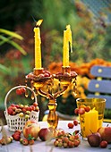 Apples and ornamental apples lying around glass candlestick