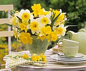 Vase of daffodils on table laid for coffee