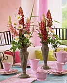 Pink crockery & arrangement of lupins, marguerites, ragged robin