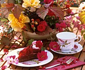 Himbeerkuchen mit Rosenblüten, Tasse und Schale mit Blumen