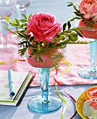 Ranunculus with pistachio foliage in glass, notebook & pen 