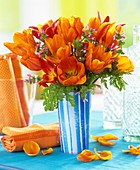 Orangefarbene Tulpen mit Gundermann in blaugestreifter Vase