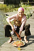 Young woman sitting on landing stage seasoning couscous salad