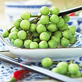 Grüne Miniauberginen auf asiatischem Teller
