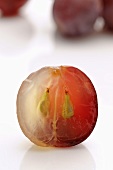 Half of a red grape, half-peeled