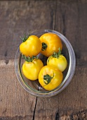 Five yellow beefsteak tomatoes in glass dish