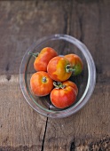 Several peach tomatoes in glass dish