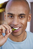 Young man biting into a pepper