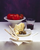 Still life: grissini, Parmesan, olives, red wine & tomatoes