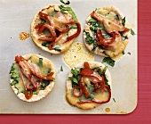 Mini-pizzas topped with spinach and strips of pepper