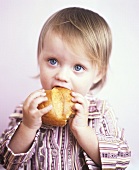 Small girl eating a bread roll